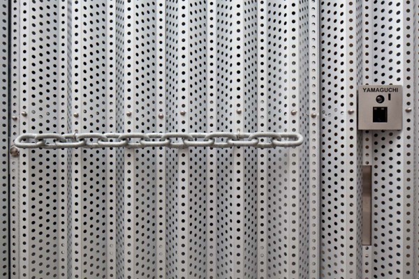 Closeup of the perforated steel facade and fused chain-link door handle. Image by Stirling Elmendorf via Shuhei Endo.