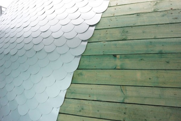 Closeup of the aluminum "scales" being added to the rink's wooden skin. Image by Marc Detiffe via L'Escault Architectures.