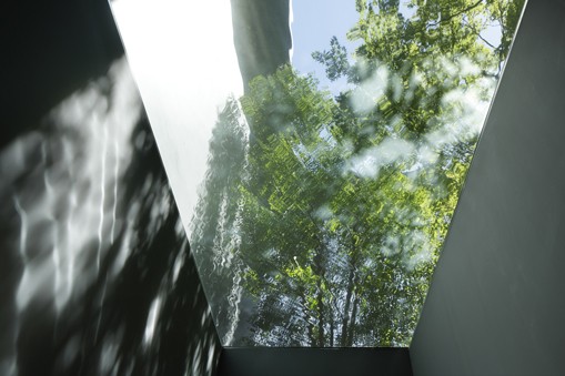 View of second-story courtyard through transparent reflecting pool, as seen from the house's ground-floor entryway. Image by Koji Fujii / Nacasa & Partners, via Hiroshi Nakamura & NAP.