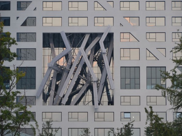 An atrium filled with jagged columns breaks open the facade of one of the eco-city. Image via Steven Holl Architects.