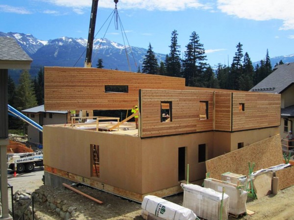 The Rainbow House under construction, showing the prefab super-insulated panel walls being lowered into place. Image via Marken Projects.