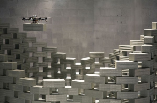 A quad-copter drone positions a foam brick over a prefab model tower in a 2012 demonstration. Image by François Lauginie via Gramazio & Kohler Architekten.